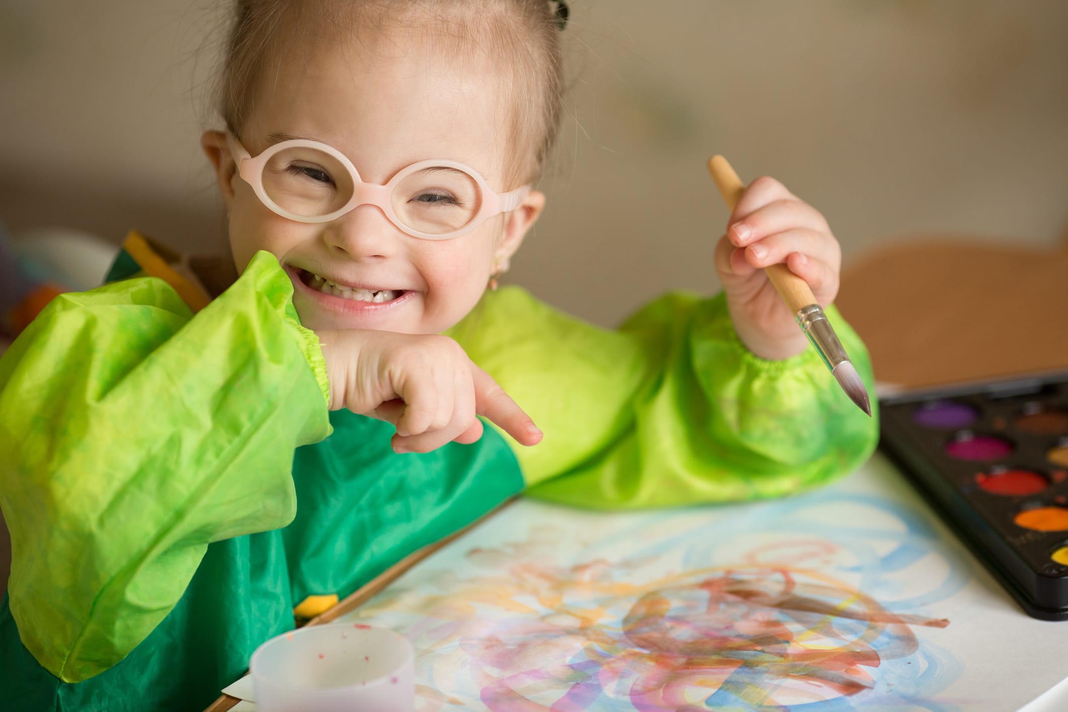 Girl, painting a picture, while sitting at a table. Adaptive programs